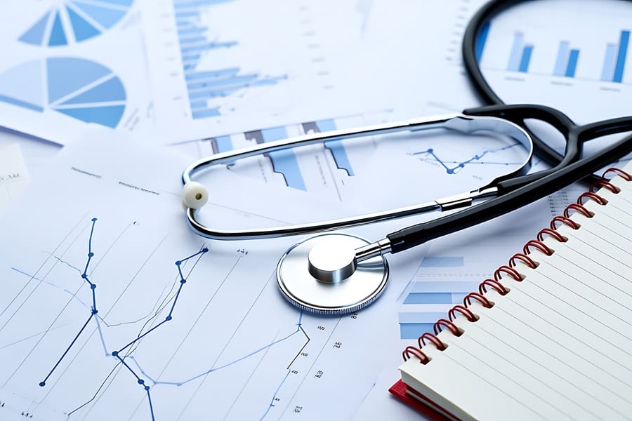 stethoscope and eyeglasses resting on medical charts and financial reports: Revenue Cycle Management